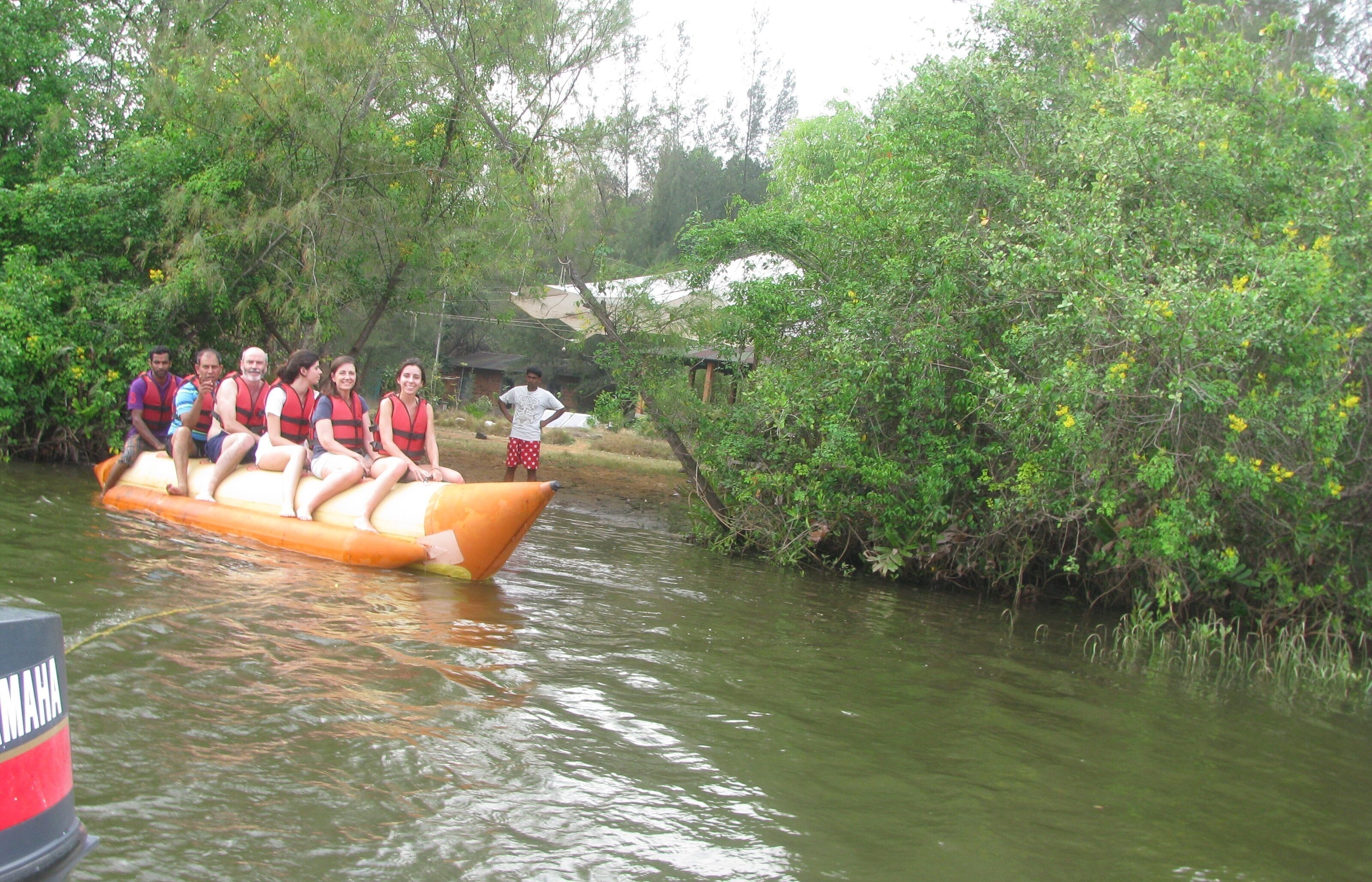 A group of people on a raft in a river surrounded by greenery.