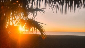 A beach scene with palm trees and the sun setting over the ocean. - El Ático Bonito Das Schöne Penthouse am Meer (Las Playitas)