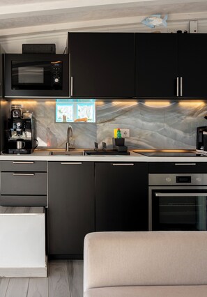 Une cuisine moderne équipée d’un four à micro-ondes, d’une machine à café et d’un four encastrés.