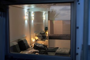 A bedroom with bunk beds, a bedside table with a lamp, and stained glass windows.
