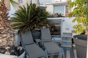 Un espace patio avec des chaises longues, une plante en pot et un bâtiment en arrière-plan.