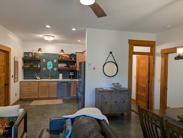 A modern kitchen with wooden cabinets, a built-in oven, and a dining area with a wooden table and chairs.