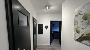 A hallway with a black door, a welcome sign, a heart-shaped decoration, and a wall with a floral pattern. - Platell Ferienhäuser Lerbach, Detached house for up to 8 people with fireplace (Osterode am Harz)