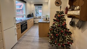 A modern kitchen with a wooden floor, a window, a microwave, a coffee maker, and a Christmas tree. - Platell Ferienhäuser Lerbach, Detached house for up to 8 people with fireplace (Osterode am Harz)