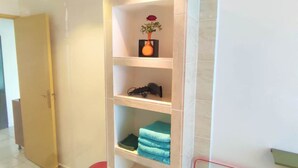 A hotel room with a large, clear shelving unit, a red stool, and a striped towel rack. - Appart T3 Tout Confort + Parking Privatif (La Rochelle)