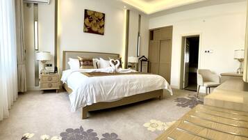 A hotel room with a large bed, bedside tables, a desk, and a wardrobe.