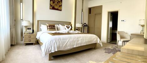 Ein Hotelzimmer mit einem großen Bett, Nachttischen, einem Schreibtisch und einem Kleiderschrank.
