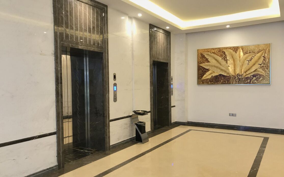 A modern elevator area with marble walls and a floor-to-ceiling mirror.