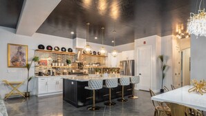 Een moderne keuken met een centraal eiland, barkrukken en hanglampen.
