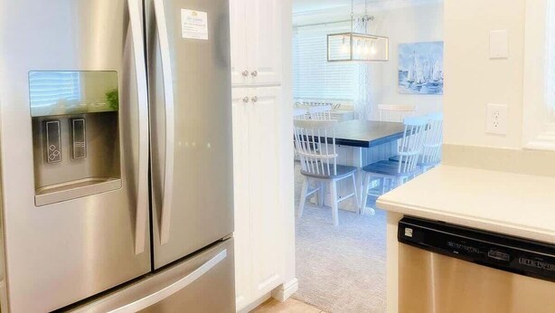 Une cuisine équipée d’un réfrigérateur en acier inoxydable, d’un lave-vaisselle et d’un coin repas avec une table et des chaises.