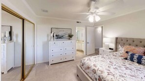 Ein Schlafzimmer mit Bett, Schminktisch und Deckenventilator.