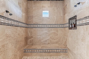 A spacious shower area with a skylight, tiled walls, and a decorative border.