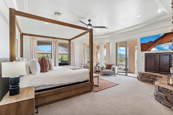 Quarto espaçoso com cama de dossel, ventilador de teto e vista para montanhas através de grandes janelas.