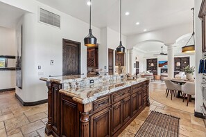 A spacious kitchen with a large island, wooden cabinets, and pendant lighting.