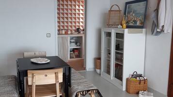 Een eetruimte met een tafel, stoelen, een hanglamp, een kast met glazen deuren en een aan de muur hangend schilderij.