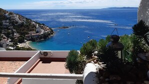 Une vue sur la côte depuis un balcon, avec un ciel dégagé, une plage et une ville qui se dessine à l’horizon.