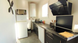A compact kitchen with a refrigerator, microwave, toaster, and a sink.