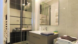 A modern bathroom with a glass shower enclosure, a vanity with a mirror, and a bathtub.