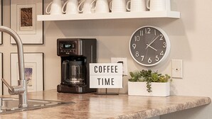 Una encimera de cocina con una cafetera, un reloj y un cartel que dice "COFFEE TIME".