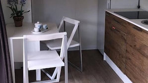 A compact kitchenette with a microwave, refrigerator, and a small dining area with a table and chairs. - Functional Mini Luxury Lodges Near Camerino (Camerino)