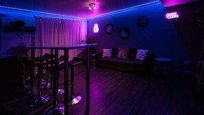 A modern living room with a bar area, a sofa, and a neon sign. - Get Away Home With Hot Tub Sleeps 4 (Peacehaven)
