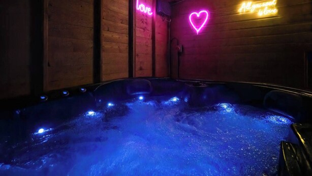 A hot tub with neon signs on the walls, surrounded by wooden paneling. - Get Away Home With Hot Tub Sleeps 4 (Peacehaven)