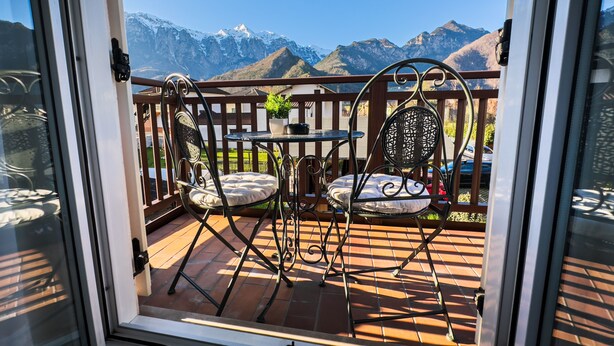 Ein Balkon mit zwei Stühlen und einem Tisch, mit Blick auf schneebedeckte Berge.