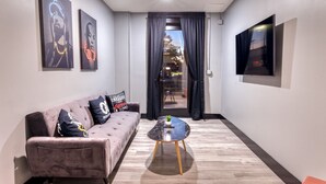 A modern living room with a sofa, a coffee table, and a TV mounted on the wall. - The Bella Downtown`s Young Money Manor Suite, 2 Queen Beds, Sleeps 4 (Biloxi)