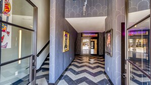 A modern hotel lobby with a chevron-patterned floor, framed artwork on the walls, and a staircase leading to the upper level. - The Bella`s Swing & Sway Suite, Sleeps 2, King Bed, Private Patio (Biloxi)