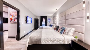 Een moderne hotelkamer met een groot bed, een televisie en kunstwerken aan de muur.