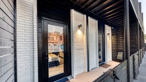 Een modern gebouw met een bakstenen gevel, grote ramen en een houten terras.
