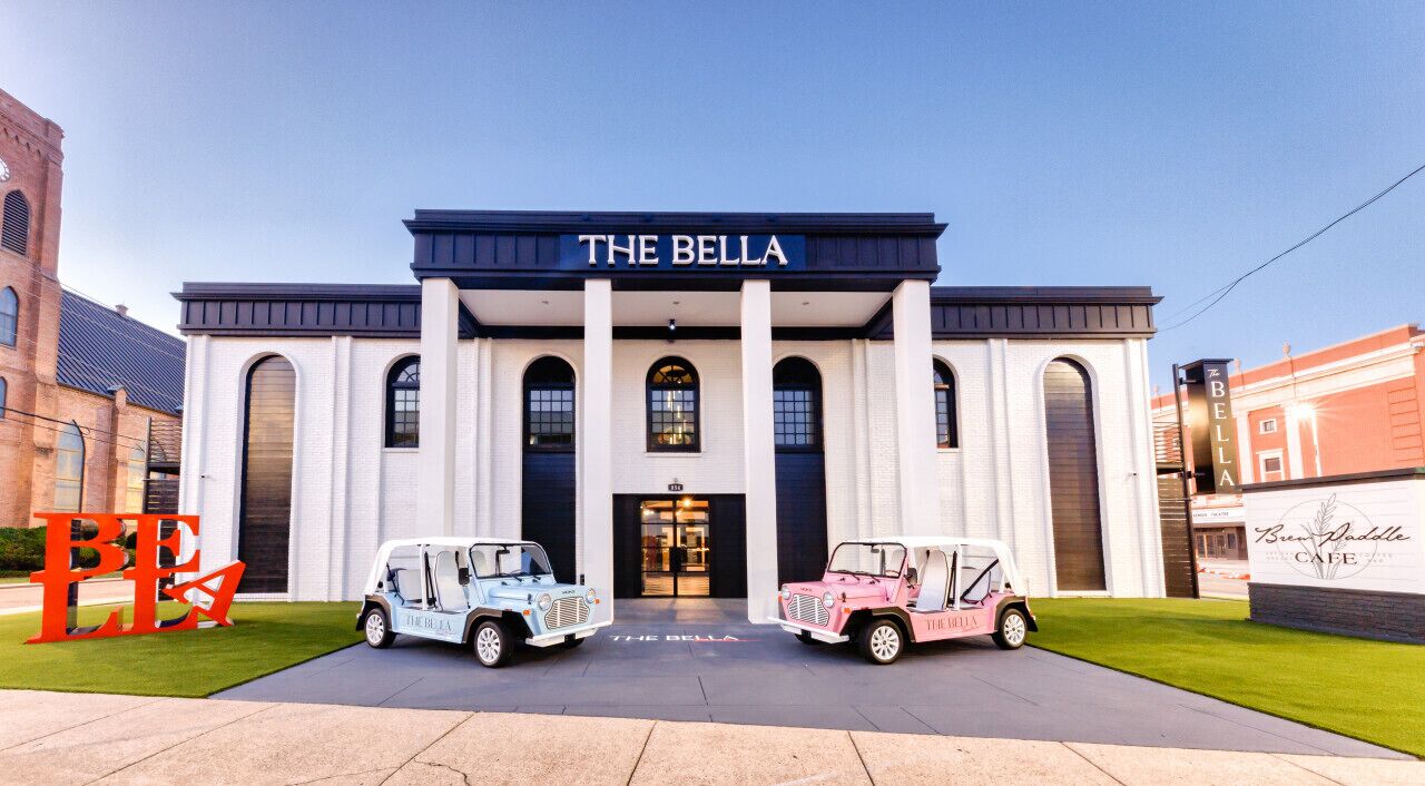 A building with a sign reading "THE BELLA" and two Jeeps parked in front.