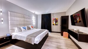 Ein modernes Hotelzimmer mit einem großen Bett, einem Flachbildfernseher und Kunstwerken an den Wänden.