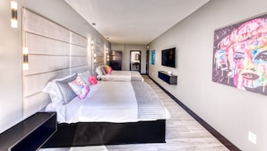 Une chambre d’hôtel moderne dotée d’un grand lit, de tables de chevet, d’un téléviseur à écran plat et d’une grande œuvre d’art accrochée au mur.