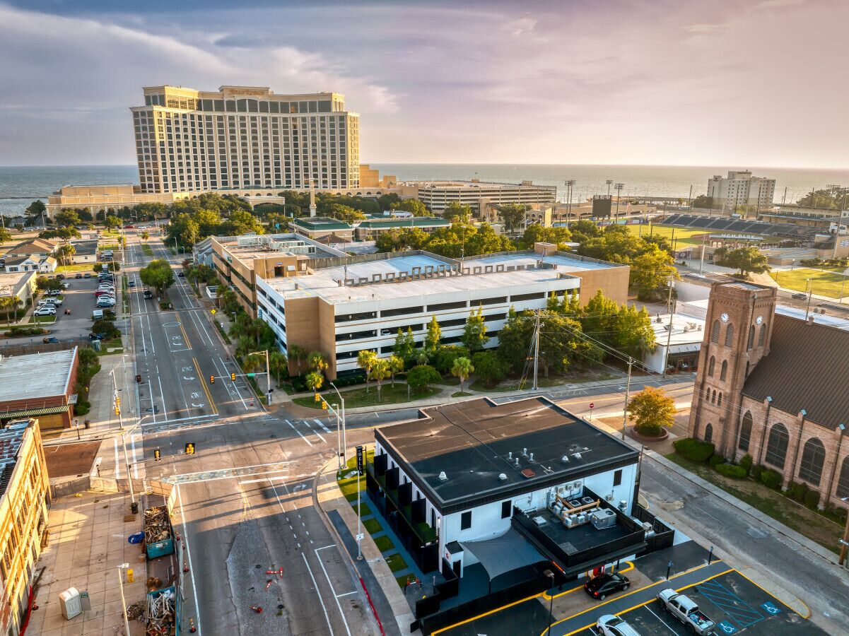 A multi-story hotel with a parking lot and a view of the ocean.