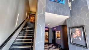 Un hall d’hôtel moderne avec un escalier, des murs à motifs et des œuvres d’art encadrées.