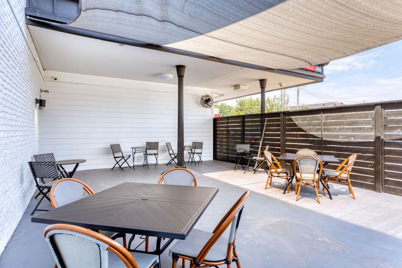 Eine Terrasse im Freien mit Tisch und Stühlen, einem überdachten Bereich und einer Umzäunung.