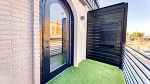 A balcony with artificial grass, a black sliding door, and a brick wall. - The Bella`s Purple Prince Suite, Sleeps 2, Private Balcony (Biloxi)
