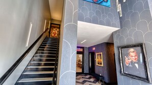 Eine moderne Hotelhalle mit Treppe, Wandmustern und gerahmten Kunstwerken.