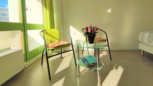 Quarto com duas cadeiras, uma com almofada e outra com uma pequena mesa contendo uma planta e alguns papéis.