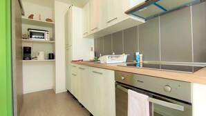 Uma cozinha moderna com armários brancos, micro-ondas, cafeteira e pia.