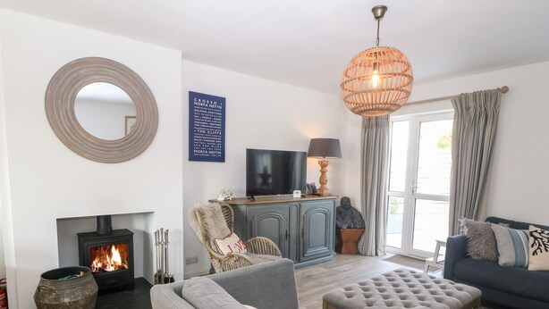 A cozy living room with a fireplace, comfortable seating, a television, and a decorative mirror. - Llwyn Onn (Pwllheli)