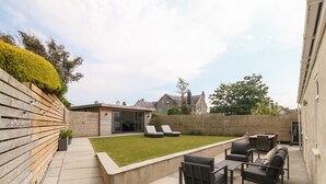 A patio with a seating area, a small pool, and a wooden fence. - Llwyn Onn (Pwllheli)
