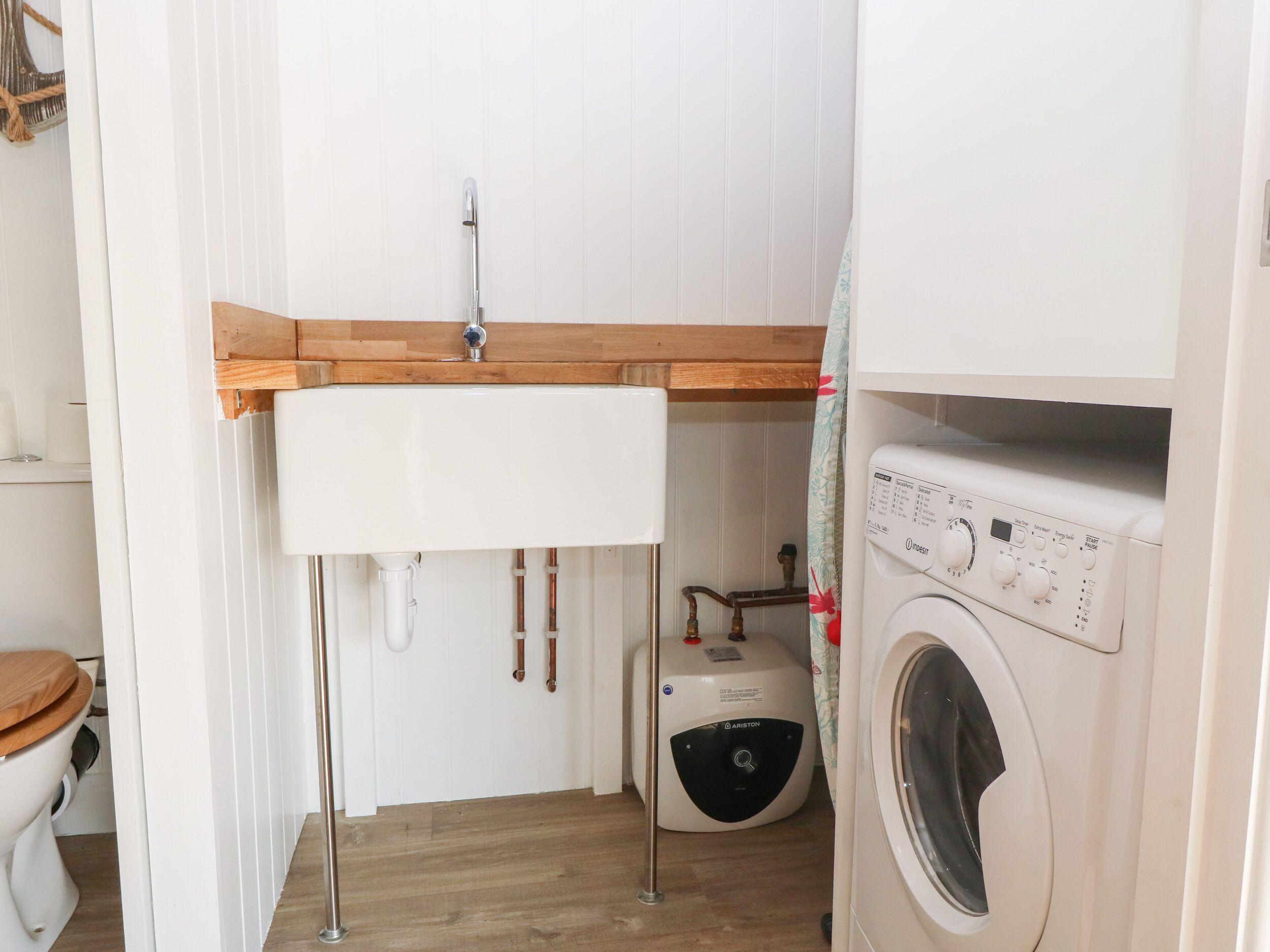 Een kleine wasruimte met een wasmachine, een wasbak en een toilet.