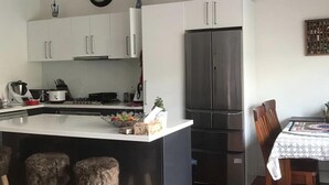 A modern kitchen with white cabinets, a stainless steel refrigerator, and a central island with stools.