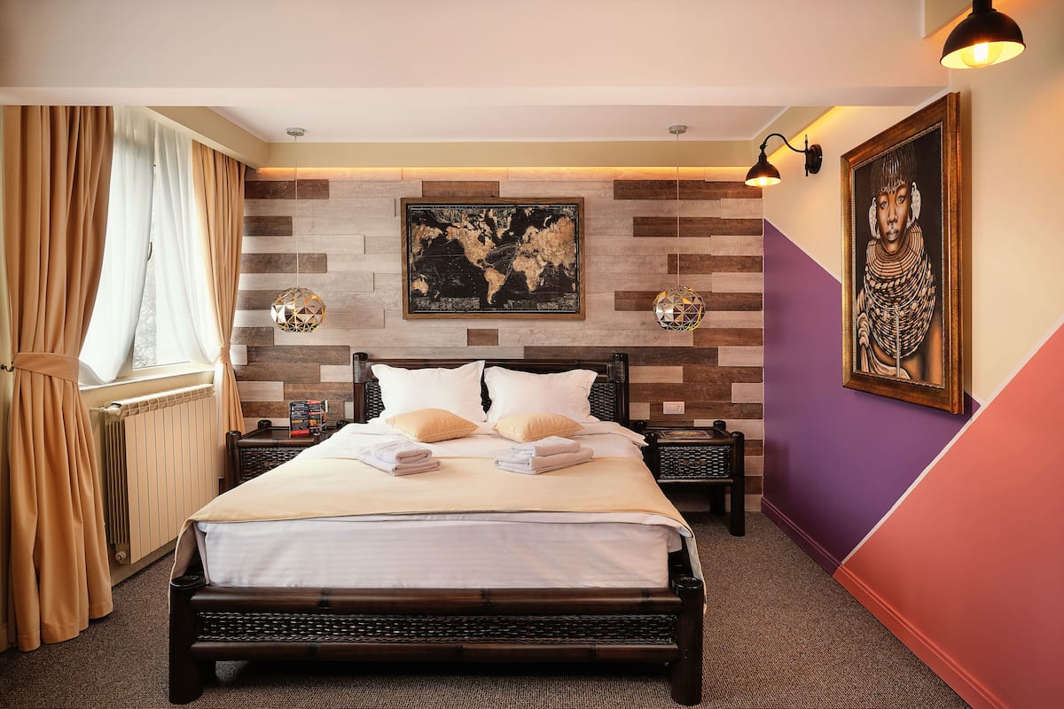 A neatly made bed with white linens, a world map on the wall, and a framed artwork.