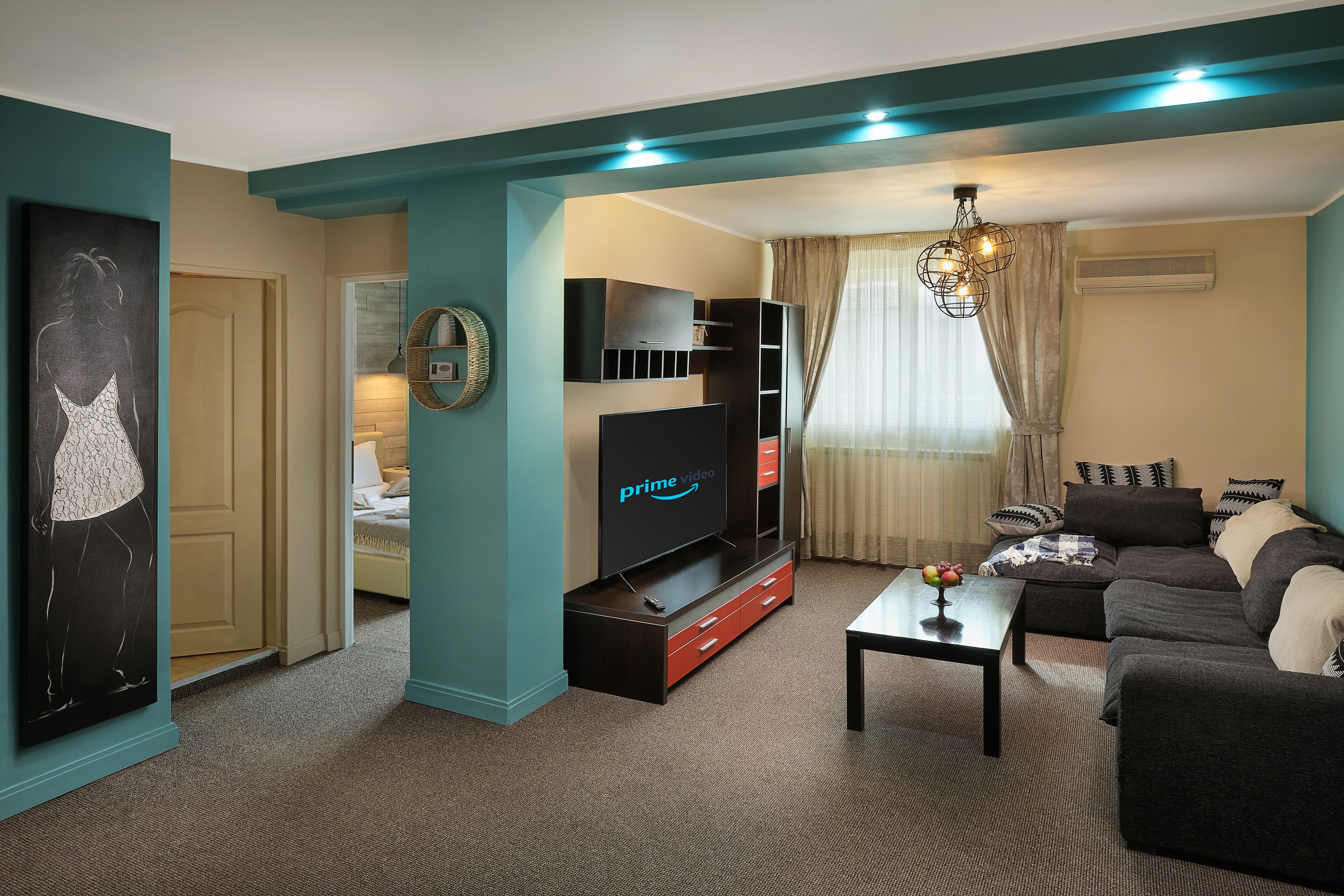 A living room with teal walls, a flat-screen TV, a sofa, and a coffee table.