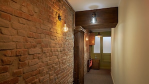 A hallway with exposed brick walls, wooden beams, and a carpeted floor. - Piata Unirii Central Apartments (Iasi)