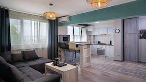 A modern living room with a sofa, coffee table, and a kitchen area with a bar counter. - Piata Unirii Central Apartments (Iasi)