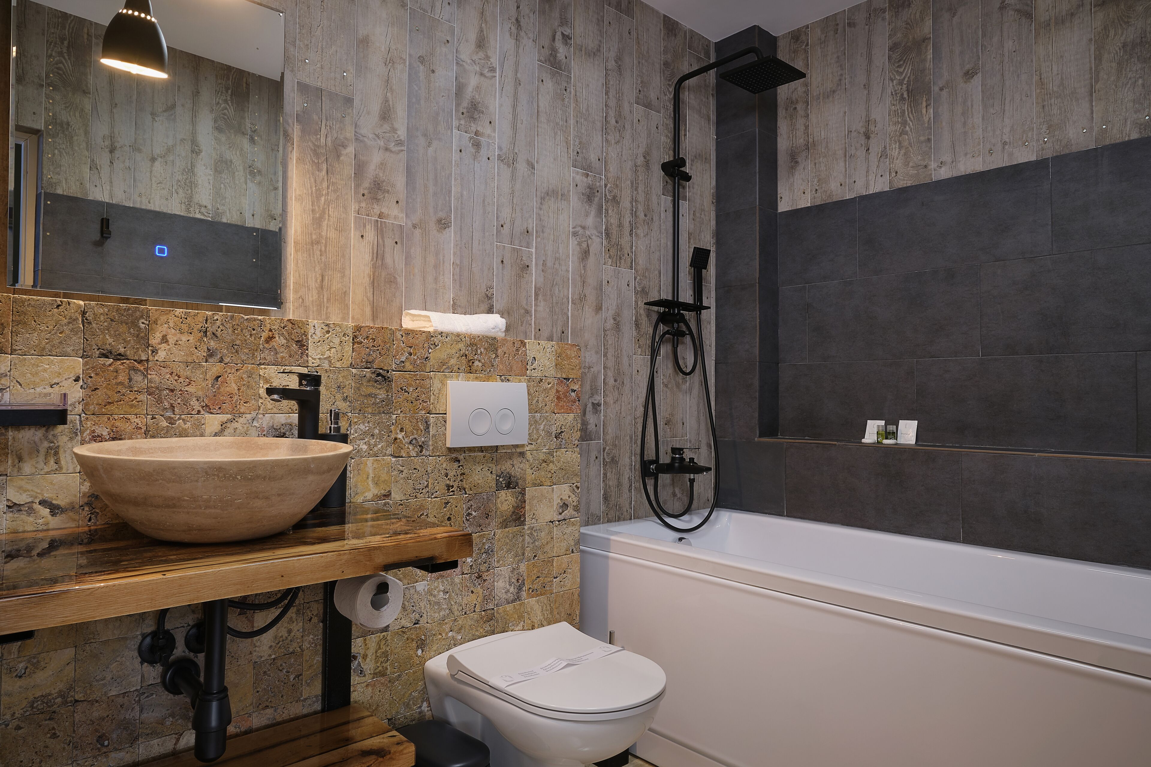 A modern bathroom with a stone sink, a toilet, and a bathtub.